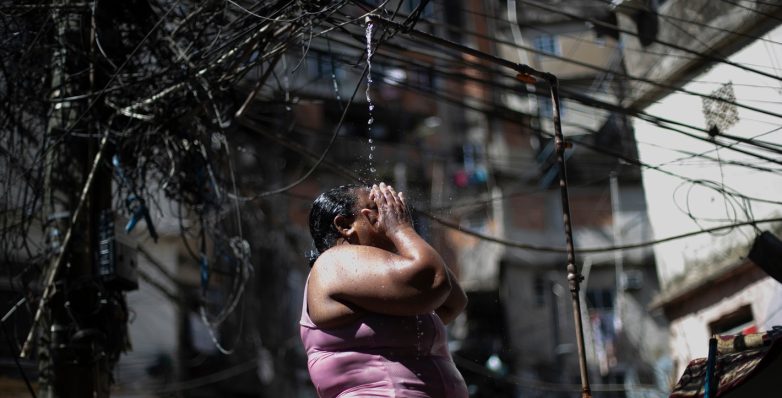 Καύσωνας στο Ρίο ντε Τζανέιρο: Μια γυναίκα δροσίζεται σε ένα δημόσιο ντους στη φαβέλα Ροσίνια