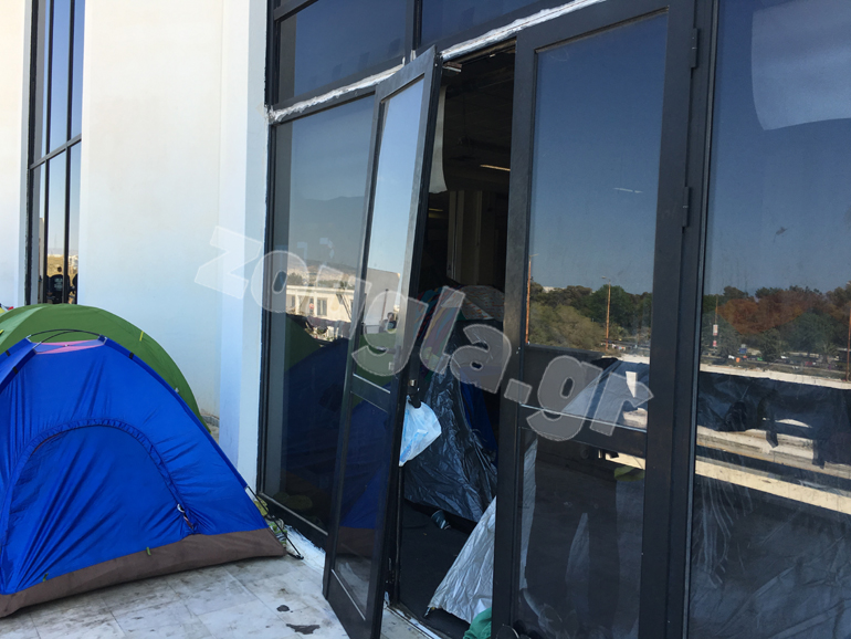 Ξεχαρβαλωμένη θύρα δίπλα στις σκηνές προσφύγων και μεταναστών