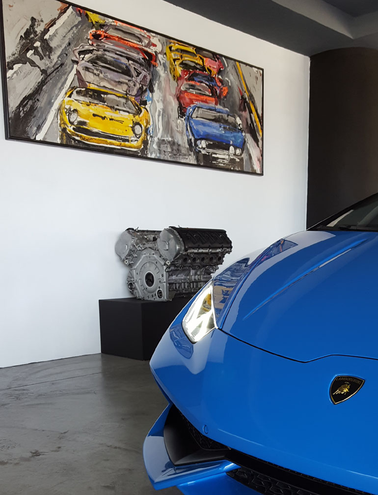 Ο... ταύρος στην αντιπροσωπεία της Lamborghini στην Ελλάδα με φόντο έναν κινητήρα Lamborghini και έναν πίνακα της ζωγράφου Μίνας Παπαθεοδώρου Βαλυράκη...