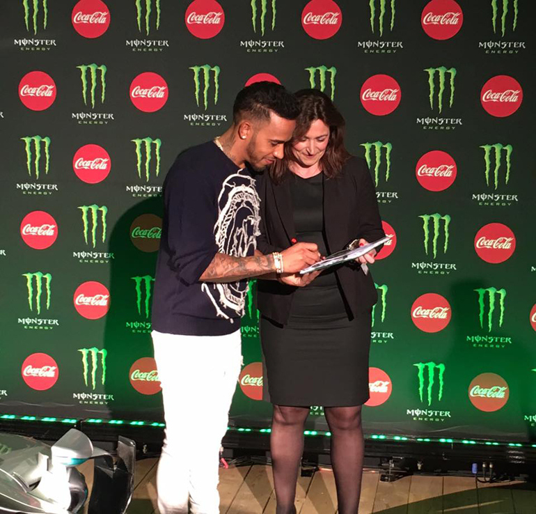 Ο παγκόσμιος πρωταθλητής Formula 1 Lewis Hamiton ήταν καλεσμένος στο παγκόσμιο συνέδριο TOΡ στελεχών της Coca Cola. Στη φωτογραφία υπογράφει αυτόγραφο στη Ρένα Γκίνη της vista events...