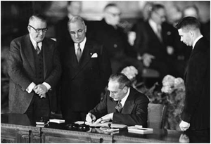 Ο τότε υπουργός Εξωτερικών των ΗΠΑ, Dean Acheson υπογράφει την αμυντική συμφωνία για την Άμυνα του Ατλαντικού  στις 4 Απριλίου 1949, υπό το βλέμμα του προέδρου Harry Truman