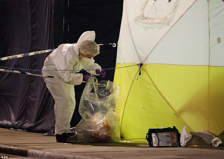 Αστυνομικός τοποθετεί ματωμένα ρούχα μέσα σε σακούλα