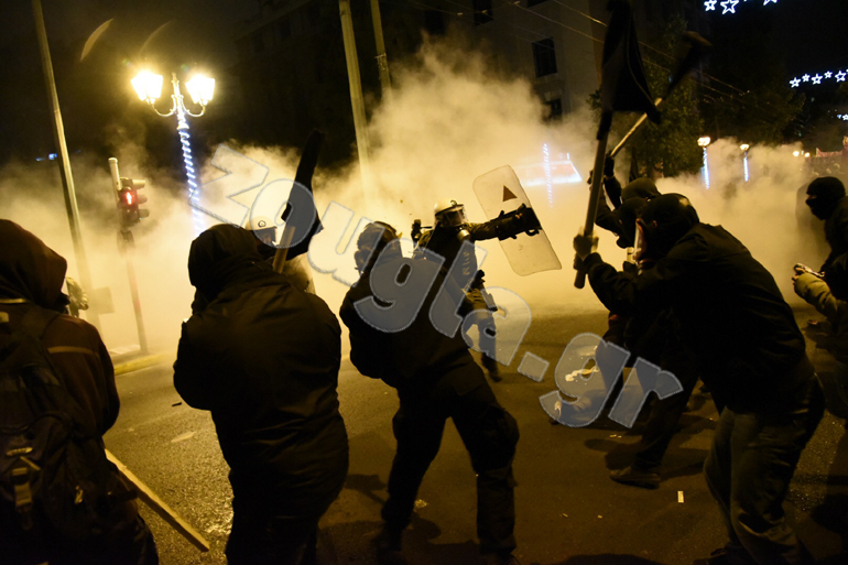 Αστυνομικός σηκώνει την ασπίδα για να προστατευτεί από τα χτυπήματα των διαδηλωτών