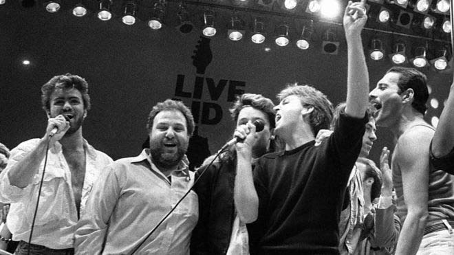 1985 – Στο στάδιο Wembley του Λονδίνου, στη φιλανθρωπική συναυλία «Live Aid famine relief» μαζί με τους Harvey Goldsmith, Bono, Paul McCartney, Bob Geldof και Freddie Mercury.