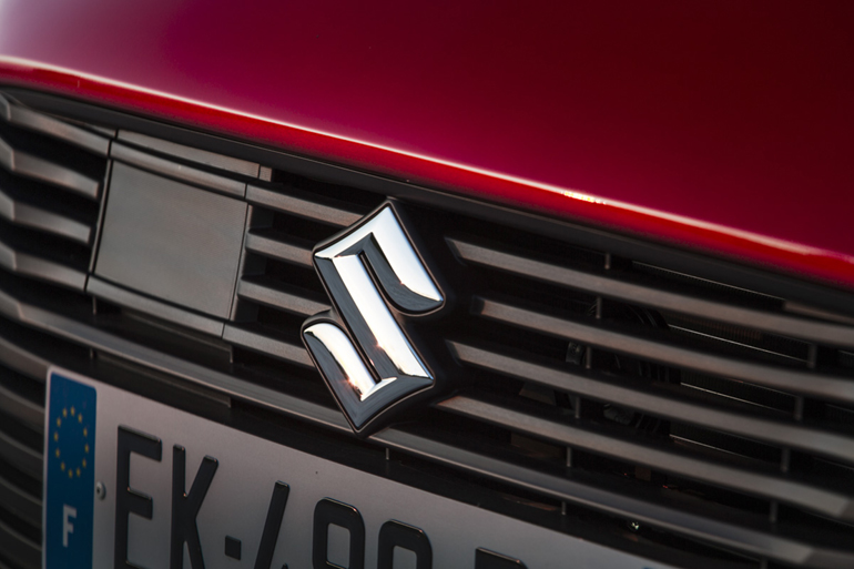 Το χαρακτηριστικό λογότυπο της Suzuki. Στα αριστερά και πίσω από το τετράγωνο πλαστικό βρίσκεται το ραντάρ που βοηθά τα διάφορα συστήματα ασφαλείας να λειτουργούν στο μέγιστο βαθμό...