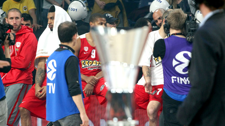 Η κούπα της Ευρωλίγκας με φόντο τους απογοητευμένους παίκτες του Ολυμπιακού