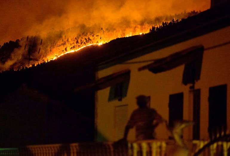 Ένας άνδρας στέκεται στο μπαλκόνι του σπιτιού του στο χωριό Avelar, και βλέπει την πυρκαγιά να κατακαίει τα πάντα στο διάβα της