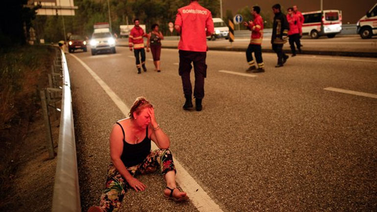 Μια γυναίκα κλαίει στην άκρη του δρόμου μη μπορώντας να συνειδητοποιήσει τι έχει συμβεί   