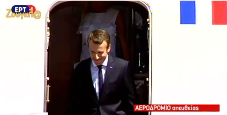 Ο Εμανουέλ Μακρόν, χαμογελαστός  κατεβαίνει τα σκαλοπάτια του προεδρικού αεροσκάφους