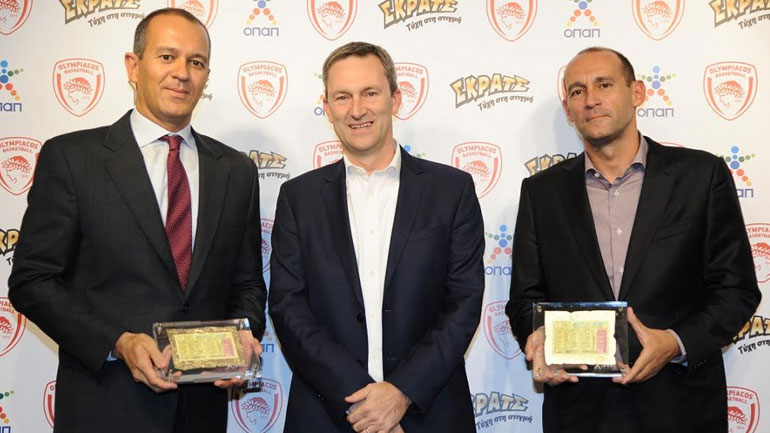 Ο Ντάμιαν Κόουπ, Διευθύνων Σύμβουλος ΟΠΑΠ, προσφέρει αναμνηστικά δώρα στους κκ. Αγγελόπουλους