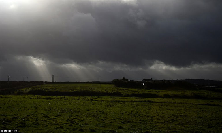 Οι ακτίνες του ήλιου λάμπουν μέσα από τα σκοτεινά σύννεφα καθώς η καταιγίδα Οφηλία χτυπά την πόλη Doonbeg στην Ιρλανδία 