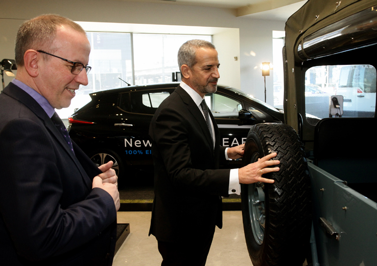 Ο Τάκης Θεοχαράκης δείχνει το αυτοκίνητο στον Πρόεδρο της Nissan Ευρώπης. Η αντίθεση πάντως των εποχών φαίνεται στη συγκεκριμένη φωτογραφία καθώς διακρίνεται το όχημα των 40 ετών και το σύγχρονο αμιγώς ηλεκτρικό Leaf στο βάθος...