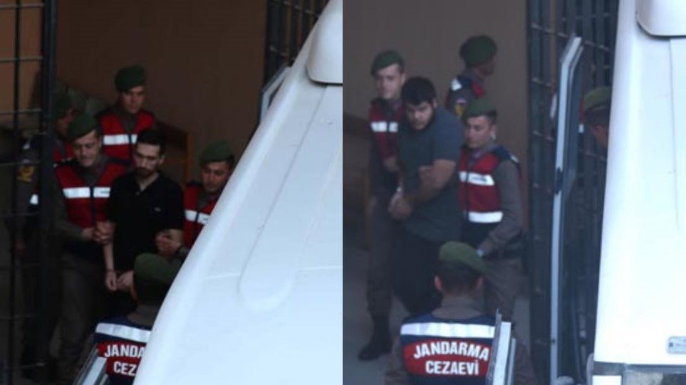 Οι δύο στρατιωτικοί, που κρατούνται επί 55 και πλέον ημέρες, εικονίζονται να βαδίζουν σιδηροδέσμιοι με χειροπέδες και να συνοδεύονται από δύο χωροφύλακες έκαστος