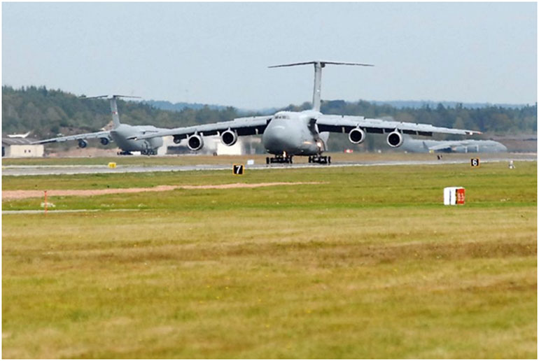 Ένα C-5 Galaxy προσγειώνεται στην αεροπορική βάση Ramstein στη Γερμανία, ενώ, ένα C-17 Globemaster III, προσγειώνεται κι ένα C-5 περιμένει τη σειρά του να απογειωθεί.