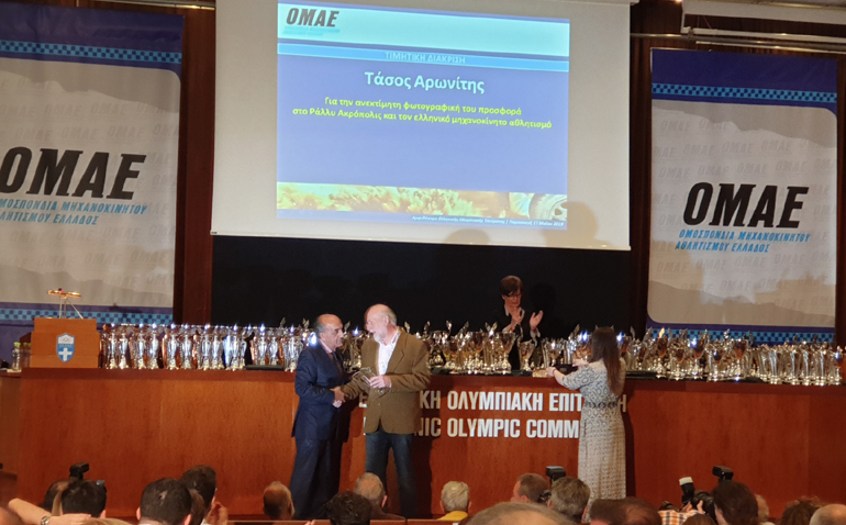 O Τάσος Αρωνίτης παραλαμβάνει τιμητική πλακέτα από τον πρόεδρο της ΟΜΑΕ Δημήτρη Μιχελακάκη