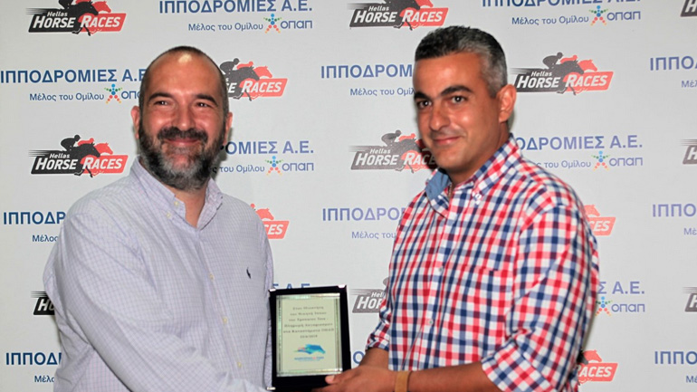 Ο Πρόεδρος και Διευθύνων Σύμβουλος της Tora Wallet Α.Ε. και Διευθύνων Σύμβουλος της Tora Direct Α.Ε Κωνσταντίνος Φρυδάκης απονέμει το Τρόπαιο TORA-ΠΛΗΡΩΜΗ ΛΟΓΑΡΙΑΣΜΩΝ ΣΤΑ ΚΑΤΑΣΤΗΜΑΤΑ ΟΠΑΠ στον προπονητή του ίππου ΠΑΡΤΙΣΙΠΕΪΤ Χάρη Χαραλάμπους.