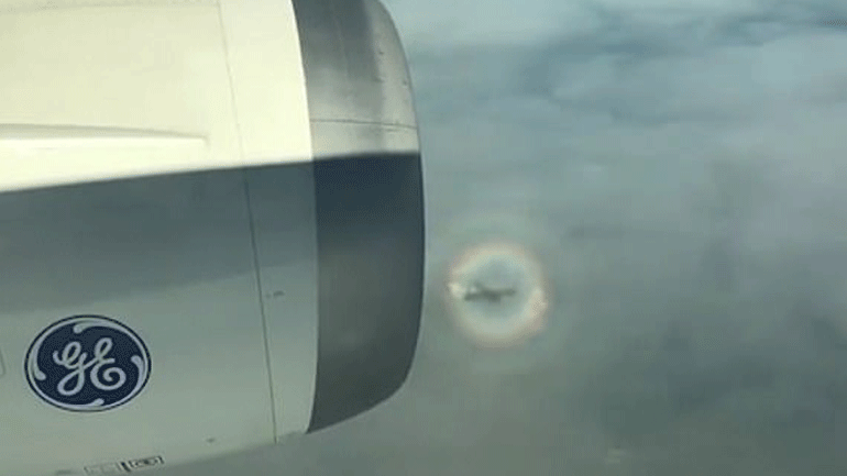 Αεροπλάνο φαίνεται να πετά μέσα σε κυκλικό ουράνιο τόξο