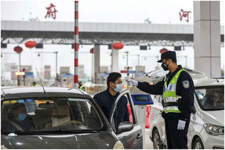 Ένας αστυνομικός στην πόλη Γιουχάν παίρνει την θερμοκρασία ενός οδηγού καταμεσής του δρόμου