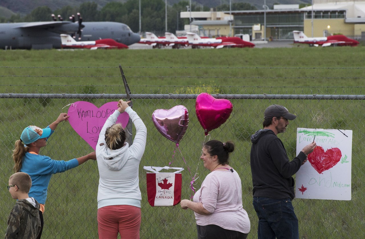 Τα αεροσκάφη Snowbirds των καναδικών δυνάμεων φαίνονται στο βάθος καθώς οι άνθρωποι τοποθετούν καρδιές και πινακίδες στο φράχτη που περιβάλλει το αεροδρόμιο στο Kamloops του Καναδά