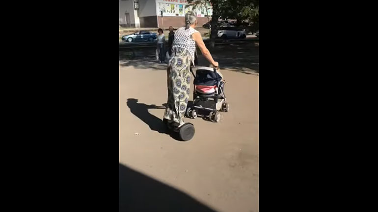 Μαμά χρησιμοποιεί ηλεκτρικό πατίνι για να σπρώξει το καροτσάκι του μωρού