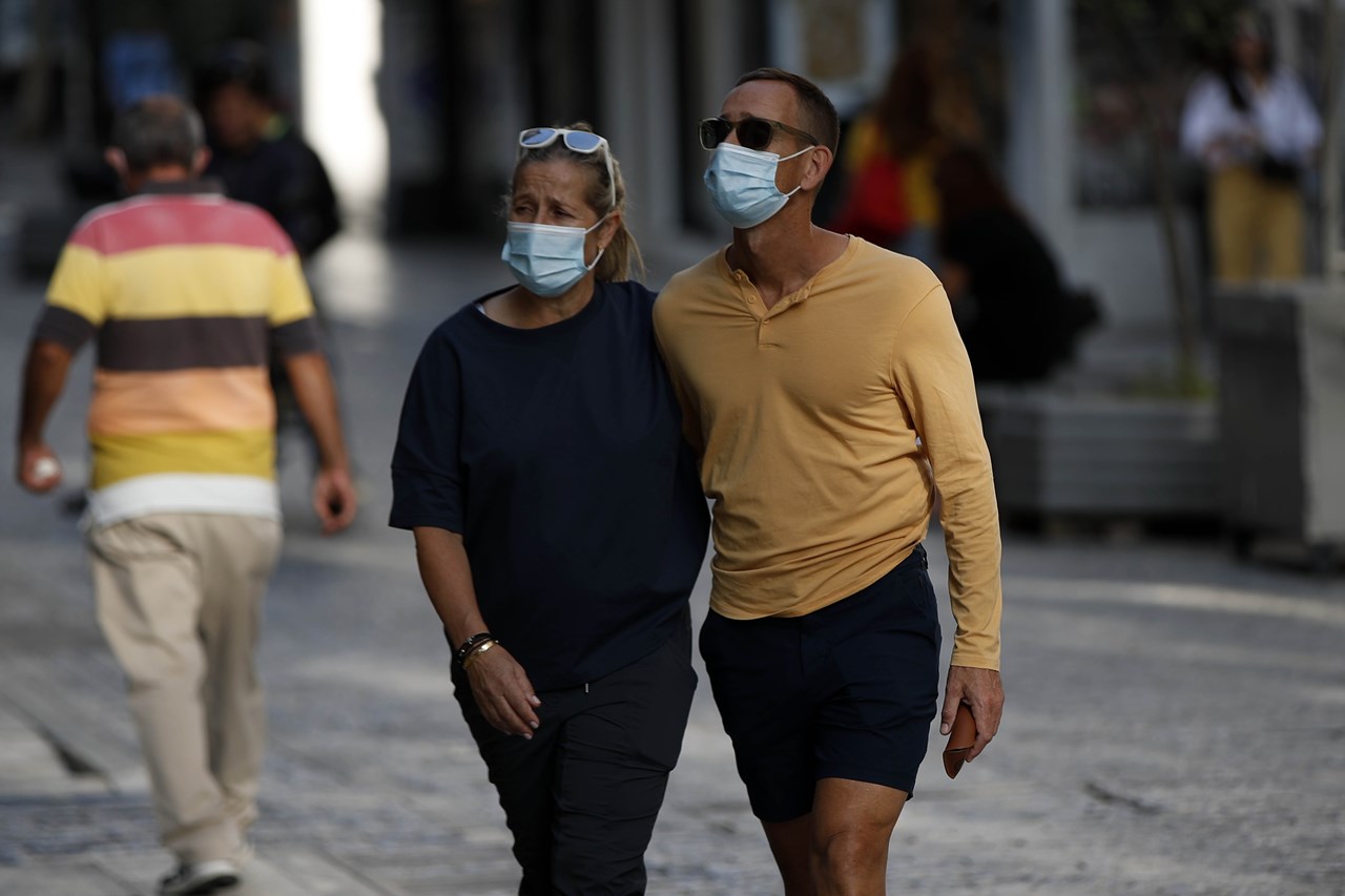 Άνθρωποι περπατούν στην Ερμού, στο κέντρο της Αθήνας, φορώντας μάσκα