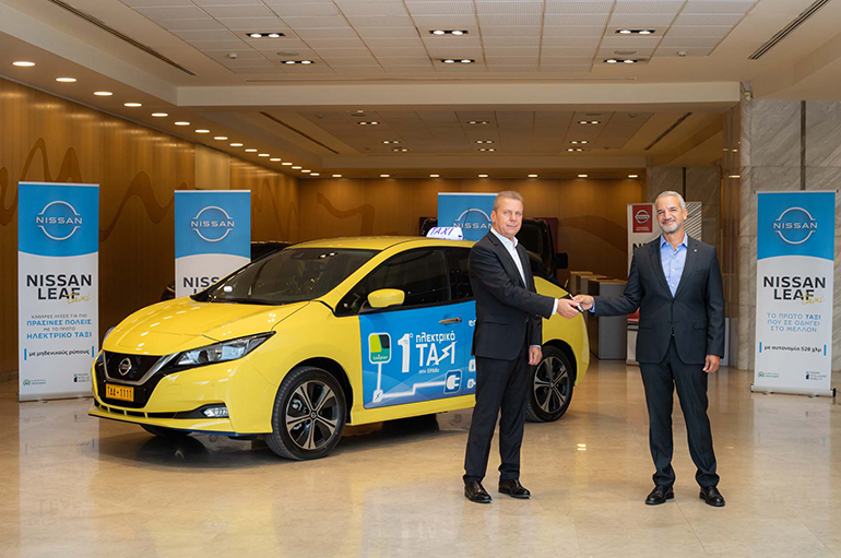 Ο Τάκης Θεοχαράκης (δεξιά) παραδίδει τα κλειδιά στον πρώτο ιδιοκτήτη ηλεκτρικού ταξί