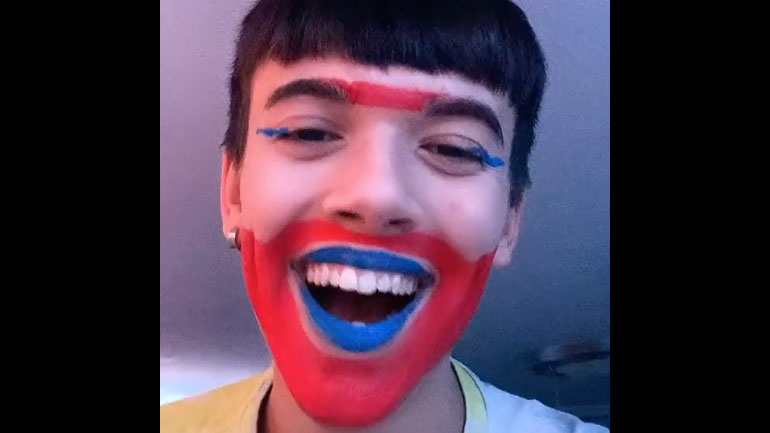 Νεαρός τραγουδά με κόκκινο και μπλε μακιγιάζ