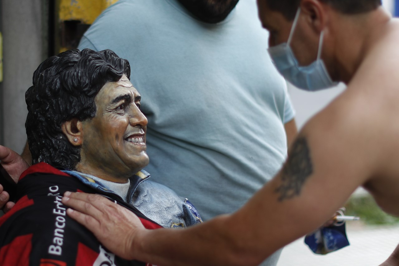 Ένας άντρας αγγίζει ένα άγαλμα του Ντιέγκο Μαραντόνα αφού έμαθε τον θάνατό του, στη γειτονιά La Boca του Μπουένος Άιρες