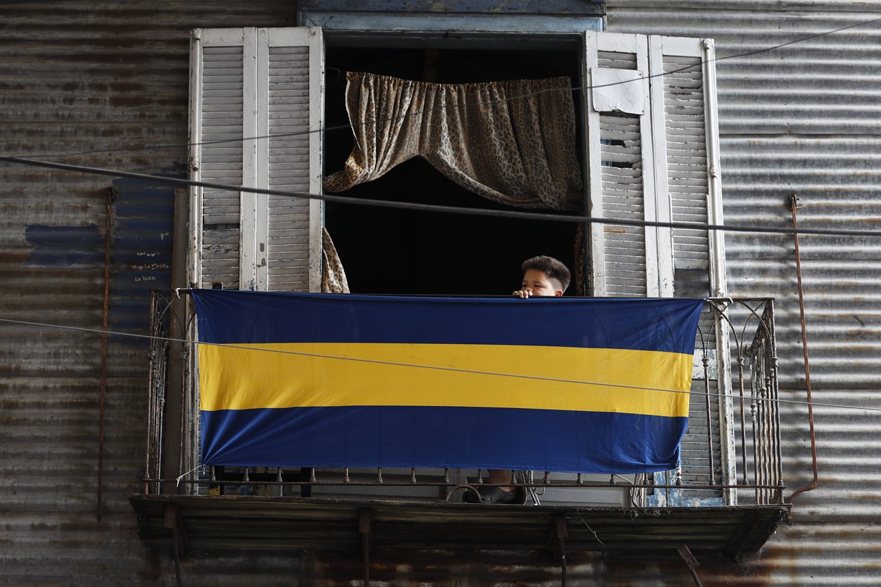 Ένα αγόρι έχει κρεμάσει στο μπαλκόνι του τη σημαία ποδοσφαίρου Boca Juniors, στη γειτονιά La Boca του Μπουένος Άιρες