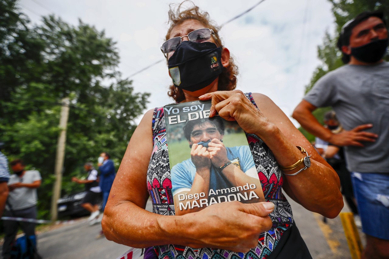 Μια γυναίκα κρατά μια βιογραφία του Ντιέγκο Μαραντόνα έξω από το σπίτι του στο Μπουένος Άιρες της Αργεντινής