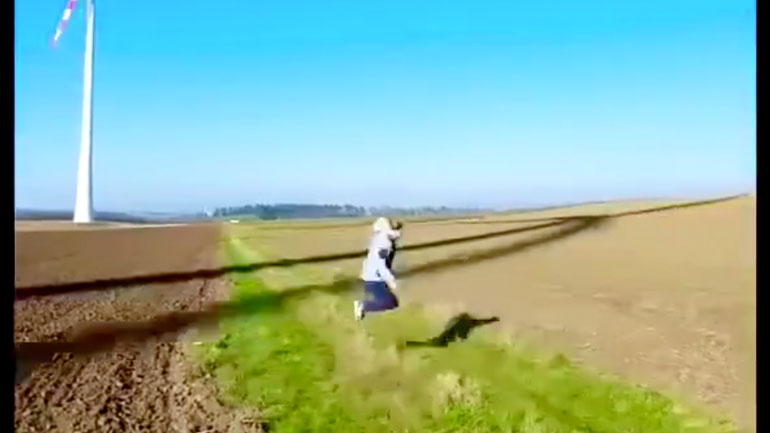 Γυναίκα παίζει με τις σκιές μιας ανεμογεννήτριας