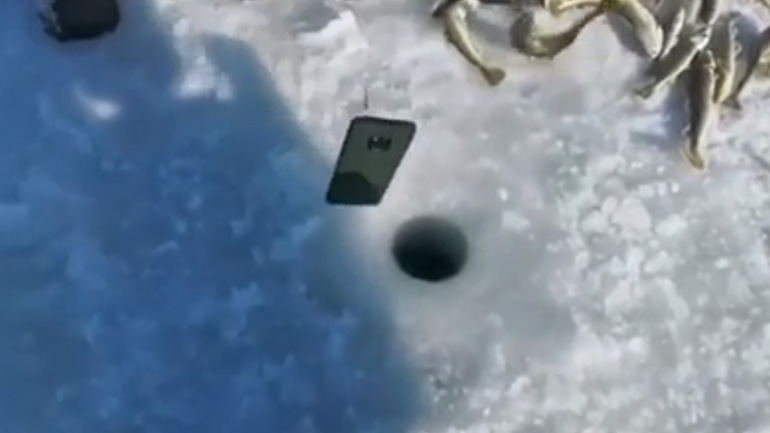 Ψαράς ελέγχει με το τηλέφωνό του εάν υπάρχουν ψάρια κάτω από τον πάγο