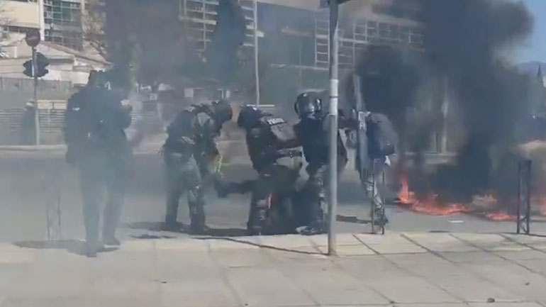 Αστυνομικοί των ΜΑΤ σβήνουν φωτιά στο πόδι διαδηλωτή που είχε ρίξει μολότοφ