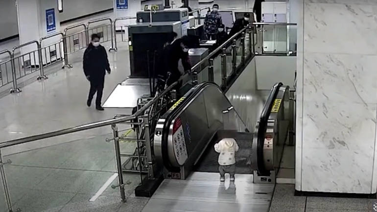 Φύλακας πιάνει ένα παιδί από την κορυφή μιας κυλιόμενης σκάλας Φύλακας πιάνει ένα παιδί από την κορυφή μιας κυλιόμενης σκάλας