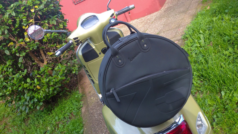 Η εκλεπτυσμένη στρογγυλή βαλίτσα με το λογότυπο της Vespa.