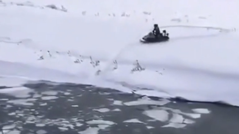 Άνδρας διασχίζει ένα ποτάμι με ένα snowmobile