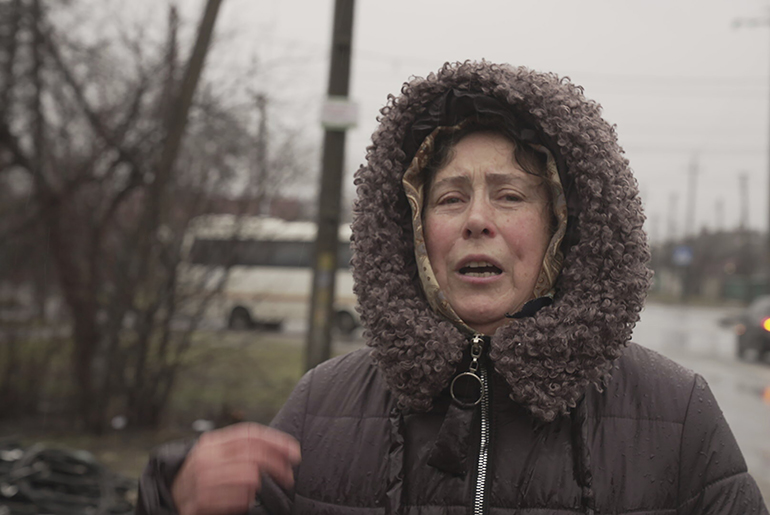 Μια γυναίκα κάνει τον σταυρό της, αντικρίζοντας τη βομβαρδισμένη γειτονιά της.