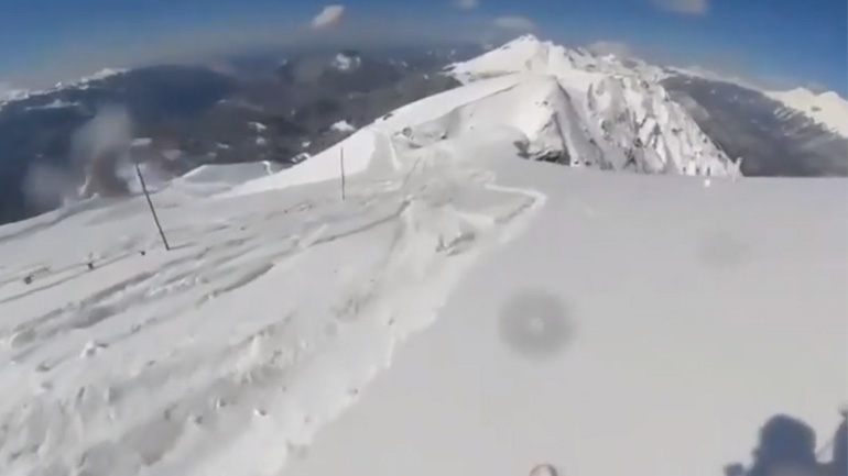 Σκιέρ με αλεξίπτωτο πλαγιάς σκάει στο χιόνι