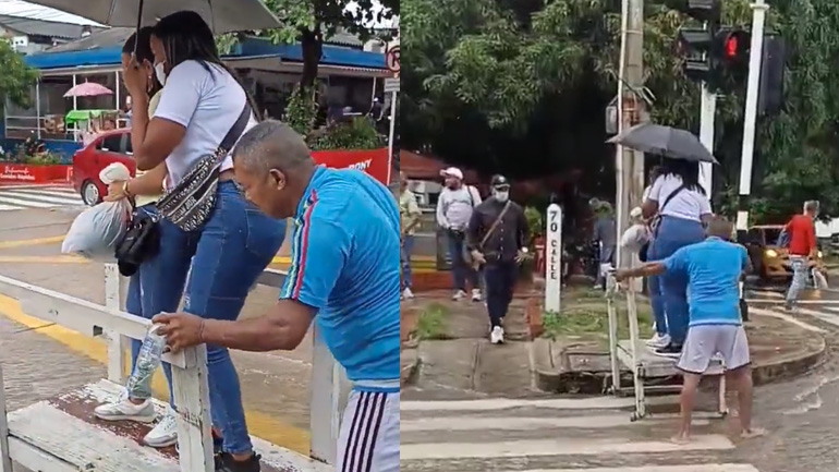 Άνδρας μεταφέρει πεζούς σε πλυμμυρισμένο δρόμο