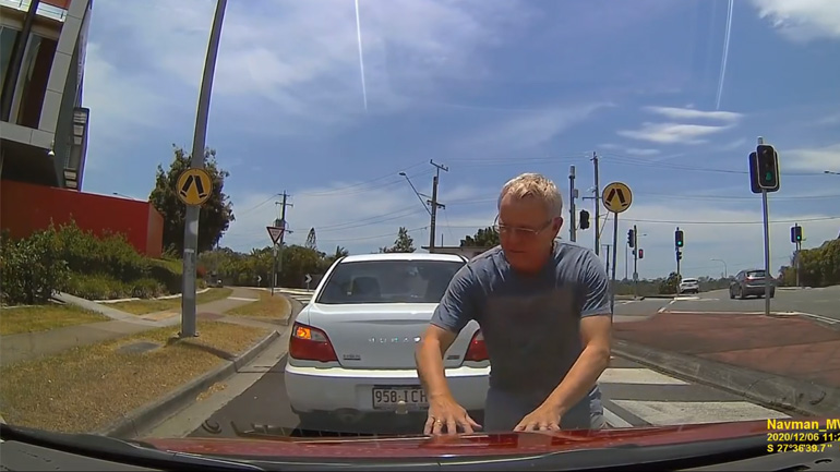 Αυτοκινητιστής σταματά στη μέση του δρόμου για να κλείσει το καπό ενός αυτοκινήτου