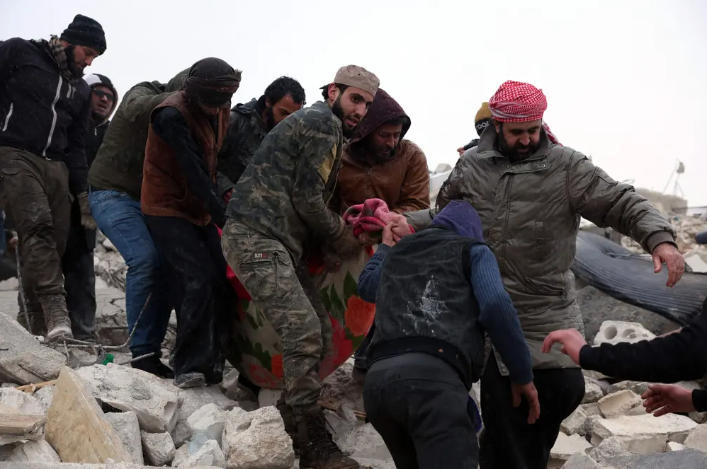 Κάτοικοι και διασώστες ανασύρουν θύματα από ερείπια ενός κτηρίου στο χωριό Μπεσνέγια της Συρίας