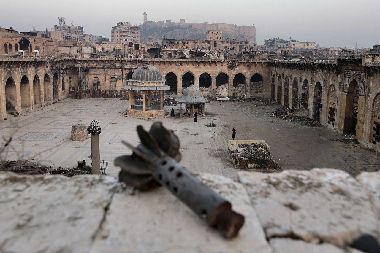 Ένας όλμος φαίνεται σε πρώτο πλάνο καθώς διασώστες αναζητούν επιζώντες στο Μεγάλο Τζαμί των Ομεϋαδών ενώ στο βάθος διακρίνεται η ακρόπολη του Χαλεπίου 
