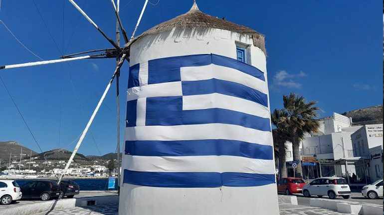 Πάρος – 25η Μαρτίου: Γιγάντια σημαία «έντυσε» στα γαλανόλευκα τον ανεμόμυλο στο λιμάνι