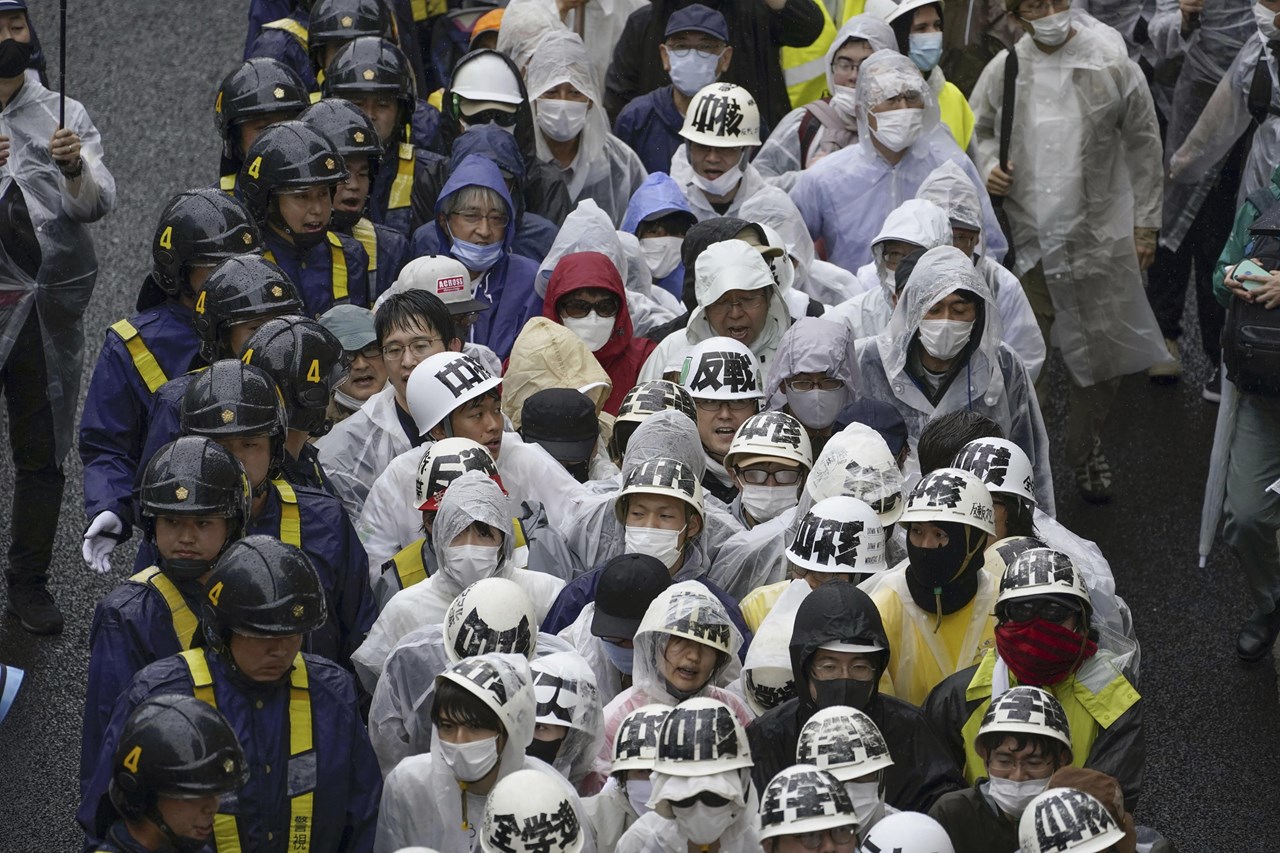 Αστυνομικοί περπατούν δίπλα σε διαδηλωτές που φωνάζουν ενάντια στις συνεδριάσεις των G7 στη Χιροσίμα