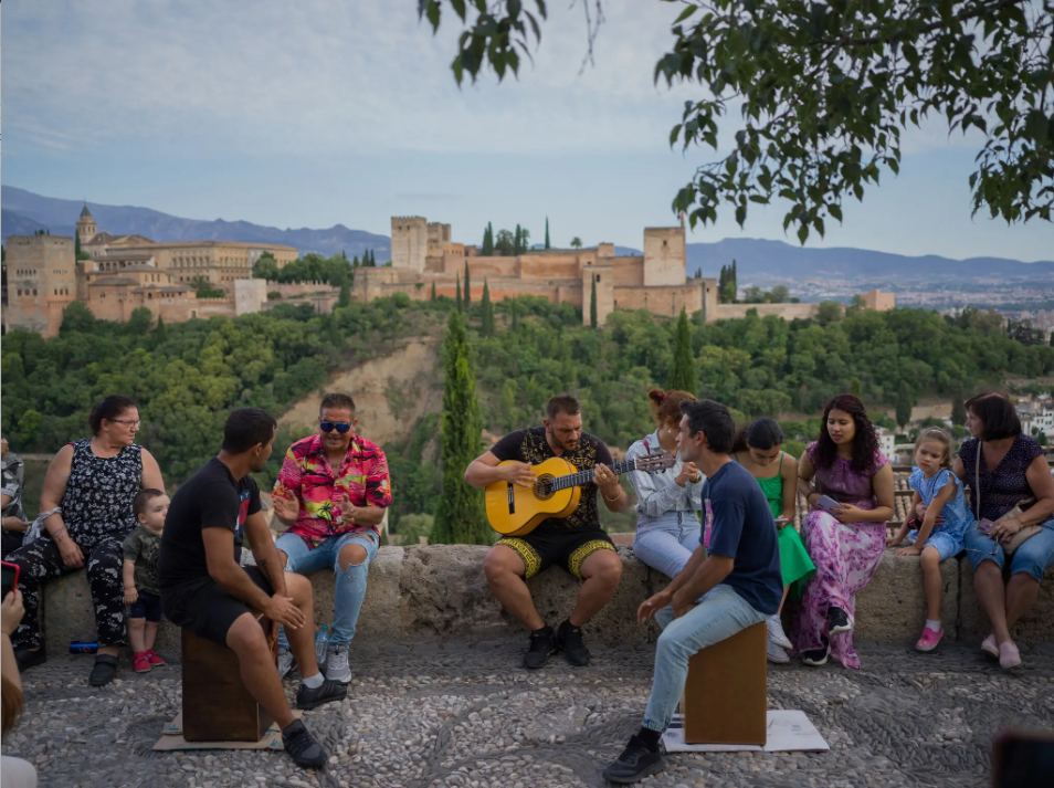 Μια ομάδα ανθρώπων που κάθεται έξω, με ένα παλάτι στο βάθος