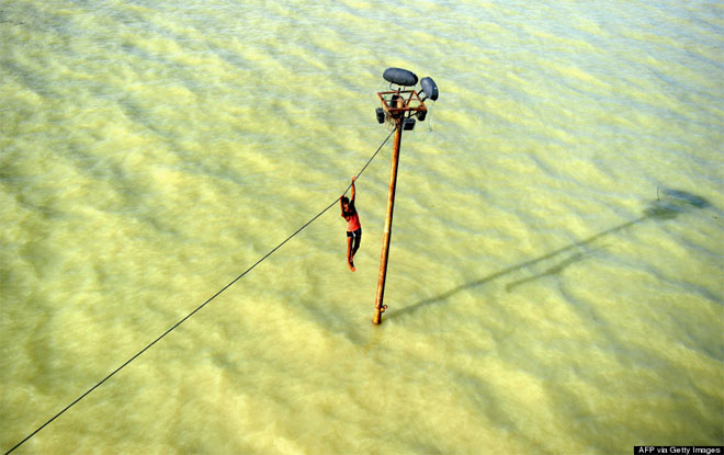 6 Αυγούστου. Μία νέα από την Ινδία κρέμεται από ένα καλώδιο υψηλής τάσης πάνω από τον πλημμυρισμένο Γάγγη ποταμό στο Allahabad. Το κορίτσι επέλεξε τελικά να πηδήξει μέσα στο ποτάμι που έπνιξε την περίοδο των μουσώνων χιλιάδες ανθρώπους.
