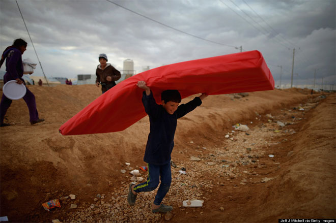 29 Ιανουαρίου. Ένας νεαρός πρόσφυγας από τη Συρία, χαμογελά παίζοντας με ένα κόκκινο στρώμα. Το αγόρι ζούσε σε καταυλισμό προσφύγων στο Mafrq της Ιορδανίας.