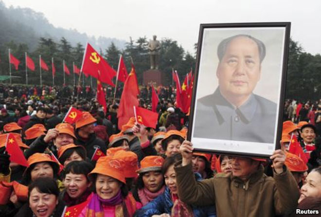 Ένας από τους συγκεντρωμένους κρατά στα χέρια το πορτραίτο του Μάο Τσε Τουνγκ, μπροστά από το γιγάντιο άγαλμα του Κινέζου ηγέτη, στις 26 Δεκεμβρίου