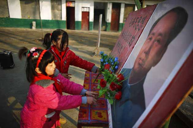 Παιδιά αφήνουν λουλούδια σε ένα από τα πορτραίτα του Μάο Τσε Τουνγκ
