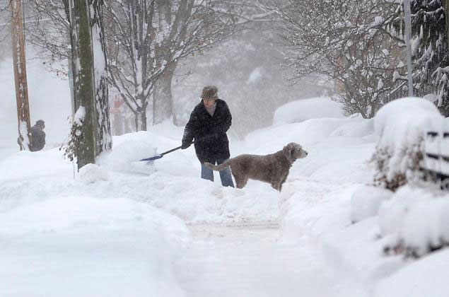 Η Michelle Kottke φτυαρίζει το χιόνι με τη βοήθεια του σκύλου της Χάρλι στο Barrington (Ιλινόις), νωρίς το απόγευμα της Πέμπτης (Ιλινόις)